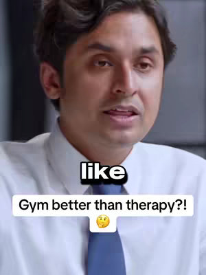 The cover image is a medium shot featuring a man with dark hair and a white dress shirt with a blue tie. The man is mid-sentence with a slight smile. Overlayed on the image is the word 'like' in a black box, over a white box that asks the question: 'Gym better than therapy?!' accompanied by a thinking emoji.