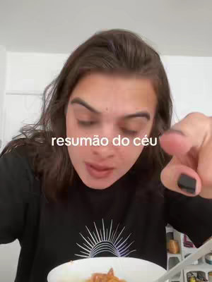 A person with dark hair and fair skin is captured from the chest up, looking directly at the camera while speaking. The cover image includes the words "resumão do céu" overlaid on the image. The person seems to be holding a plate with food, while pointing with one finger. The background is blurry, suggesting an indoor setting.