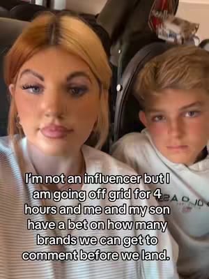 A selfie-style shot featuring a woman and a young boy, likely her son, seated indoors. The woman, positioned on the left, has fair skin, long eyelashes, and blonde hair with darker roots, and is wearing earrings. The boy, situated on the right, has short blonde hair. The background behind them is blurred, suggesting an interior setting, possibly a vehicle. On the forefront, white text overlay appears.
