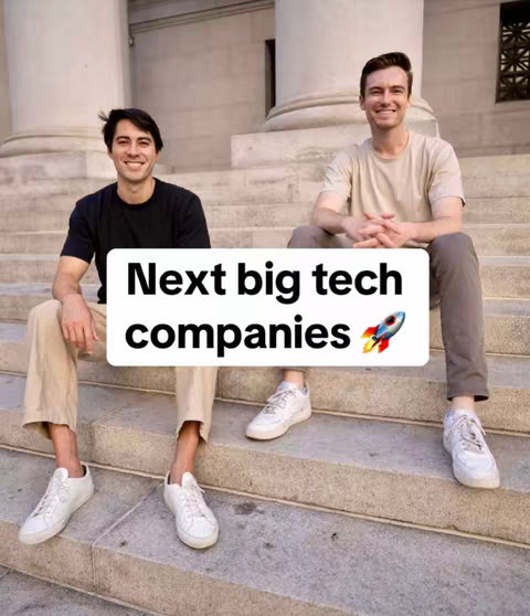 Two young men are sitting side-by-side on a set of concrete steps, posing for the camera. They're both smiling and looking toward the viewer. The background features a large stone building with columns. The top of the image features a white overlay with large black text that says 'Next big tech companies' and a rocket emoji.