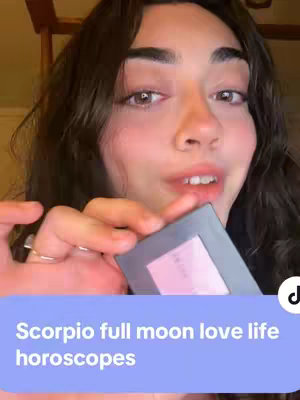 The cover image shows a young woman in a close-up shot, holding a small, rectangular makeup compact. She is looking at the camera with slightly parted lips. Below her face, a light blue banner displays white text, and there are elements of a wooden structure in the background.