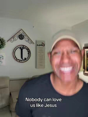A man with a shaved head is smiling directly at the camera with a blurry background of a room. The text overlay reads: 'Nobody can love us like Jesus'