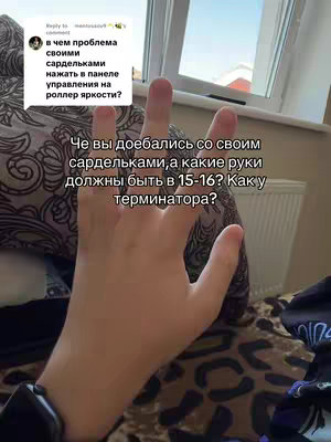 The image shows a person's hand, with fingers spread, against a background of a patterned comforter and a window. Text overlays appear in the top left and bottom center, with questions and statements in a Cyrillic script. The lighting appears to be natural.