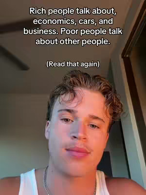 A young man with light skin and styled, light-brown hair is centered in a selfie-style shot. He wears a white tank top, and the image is lit with warm, natural light emphasizing his face. The background is a light-toned room, where the text is overlaid: rich people talk about economics, cars, and business. Poor people talk about other people. (Read that again)