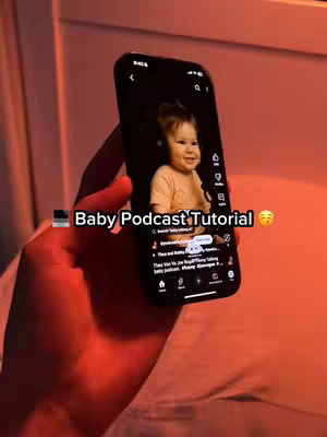 A hand holding an iPhone with the TikTok interface open. On the screen is a video of a baby, and the creator is filming it while in bed. The text "Baby Podcast Tutorial" is overlaid on the image.