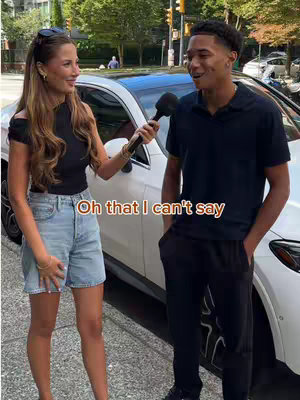 A woman interviews a man on a city street. The woman is holding a microphone, and the man is standing next to a white car. Text overlayed on the image reads, “Oh that I can’t say”.