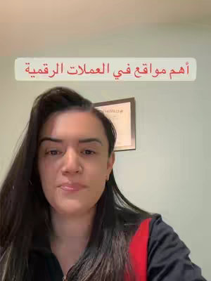 A woman with long dark hair is centered in the frame, her expression neutral. Above her is a light-colored, rounded rectangular text overlay with the Arabic inscription 'أهم مواقع في العملات الرقمية', which translates to 'The most important sites in cryptocurrencies'. Behind her, the background consists of a light-green wall, a framed certificate, and the corner of a room, all bathed in natural light suggesting an indoor setting.
