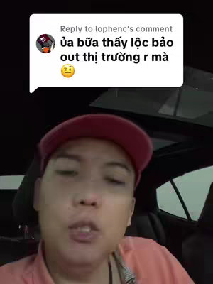 A man wearing a red cap and a salmon-colored shirt is inside a car, looking directly at the camera with his mouth open as if he is speaking. A comment box is visible above the man with text in Vietnamese.