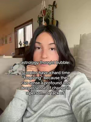 A young woman with dark hair is facing the camera. The backdrop shows hints of a room with a partially visible window, a plant, and some decorative items. Text overlays on the image appear to be in the format of a "thought bubble"