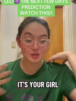 A woman with glasses is centered in the frame, speaking. She wears a green t-shirt and has brown hair. Behind her is a light-colored door and a wall. The text overlays are a rectangular green box with white text stating "LEO ♌ THE NEXT FEW DAYS PREDICTION WATCH THIS!!". Below, in a black box with white text, it says "IT'S YOUR GIRL".