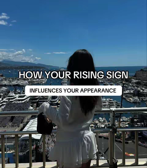 A woman with long dark hair stands on a balcony overlooking a harbor filled with boats. Text overlays read "HOW YOUR RISING SIGN" and "INFLUENCES YOUR APPEARANCE".
