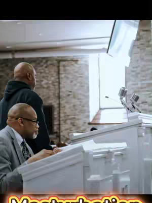 The cover image shows a scene inside a church. Two men are visible; one is in a suit, standing behind a podium, and another is in a hoodie standing behind him. The foreground features parts of a white podium with microphones.
