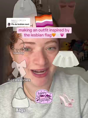 The cover image features a woman with fair skin and light red hair looking at the camera with a welcoming expression. A text overlay states, "making an outfit inspired by the lesbian flag." The woman has several graphic overlays, including a heart, a comment box, and several fashion accessory illustrations.