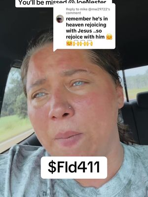A woman with fair skin and light blue eyes is captured in a selfie-style shot, possibly inside a vehicle. She has a neutral expression but with a visible redness to the skin. A white rectangle at the bottom contains the text '$Fld411'.