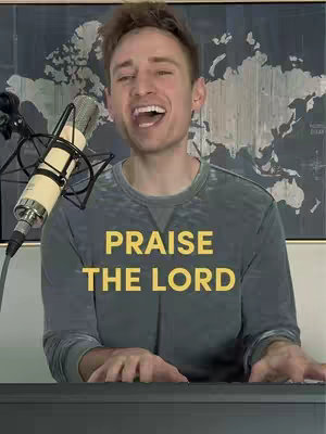 A man with short brown hair is singing into a microphone while playing a keyboard. The text overlay says "PRAISE THE LORD" in yellow.