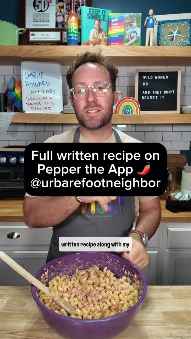 The cover image features a man in a kitchen setting, holding a purple bowl of pasta salad. A text overlay states a recipe is available, mentioning an app for the recipe. The background includes kitchen elements: shelves with books, a board with a handwritten note, and decorations.