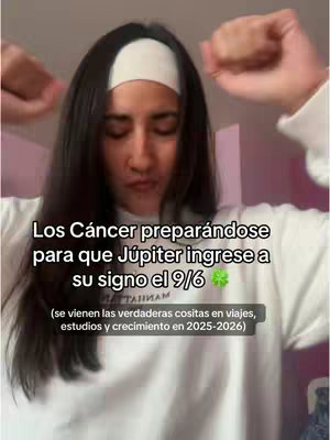 A woman with long dark hair and wearing a white headband and a white shirt is shown in front of a light pink background. She is holding her arms up near her face appearing to be excited. Text overlays in white.