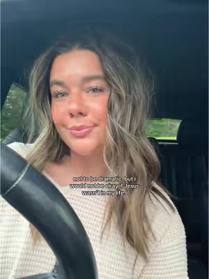 The cover image is a selfie of a young woman inside a car. She has long, wavy blonde hair and is wearing a light-colored sweater. The text overlayed on the image reads: "not to be dramatic, but i would not be okay if Jesus wasn't in my life."