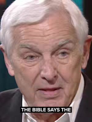 A close-up shot of an older man with gray hair, looking directly at the camera. The man is well-groomed, wearing a dark blazer over a white collared shirt. Below him, a black bar displays white text.