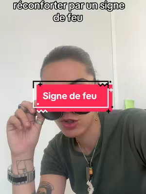 A person with dark hair and sunglasses is holding them up with one hand, their face in the focus. Text overlays are present in the upper and middle portions of the image against the natural background setting.