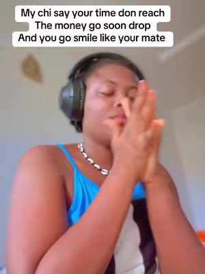The cover image shows a woman with dark skin in a selfie-style shot, looking upward with her hands clasped together in front of her face. She's wearing a blue tank top, a necklace, and headphones. The background is a light, blurred interior space. Text overlays at the top of the image. 
