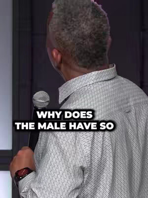 A man with gray hair is seen from the back, wearing a white button-up shirt with a subtle pattern, holding a microphone. Text overlayed on the image asks a question with bold white font against a black background.