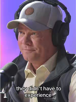 A medium shot shows a man with short hair wearing a grey baseball cap, headphones, and a dark jacket. Text overlayed at the bottom of the image.