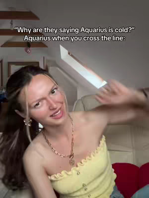 A woman in a yellow top is smiling and gesturing towards the camera, with text overlays. The background is a softly lit room.