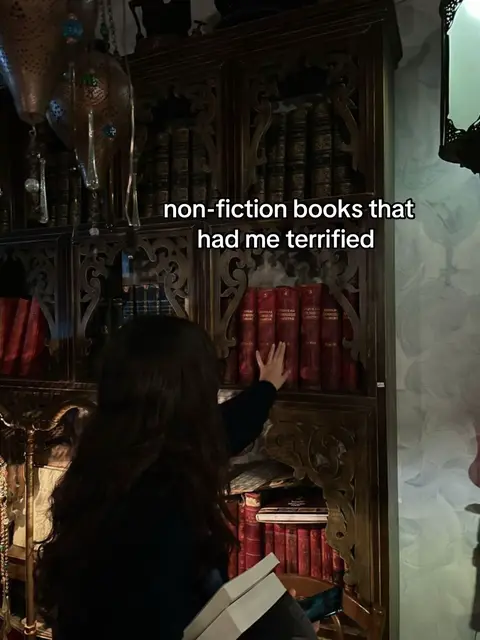 The image displays a woman with dark hair reaching towards a bookshelf filled with old, red-covered books. Text overlay reads 'non-fiction books that had me terrified'. The background shows ornate wooden shelves and a dimly lit interior.