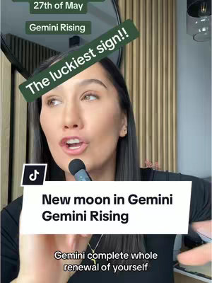The cover image is a vertical video frame featuring a woman speaking towards the camera with a microphone. She is wearing a dark top. Behind her is a window covered with a light colored, vertical striped panel. The frame has multiple overlaid text boxes - one with the text "The luckiest sign!!" and other various text boxes with the information about new moon and the astrologic sign.