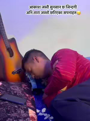 The image shows a young man lying on a bed, his head resting on a patterned pillow. An acoustic guitar leans against the wall in the background, with a phone positioned near the bed. Text is overlaid at the top of the image.