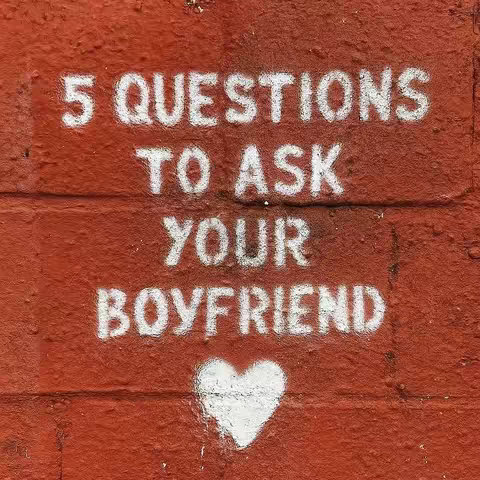 A square image featuring a weathered red brick wall. Stenciled in white, centered, are the words: "5 QUESTIONS TO ASK YOUR BOYFRIEND" followedby a white heart shape beneath at the bottom.
