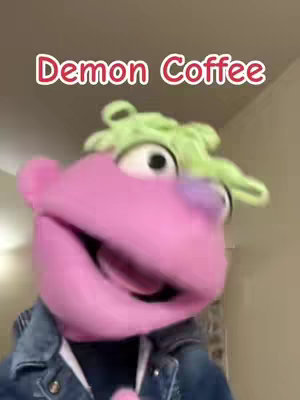 The cover image features a puppet with a light green, curly "hair" and large white eyes. It's pink and purple with a blue jean jacket, and the text overlay says "Demon Coffee".