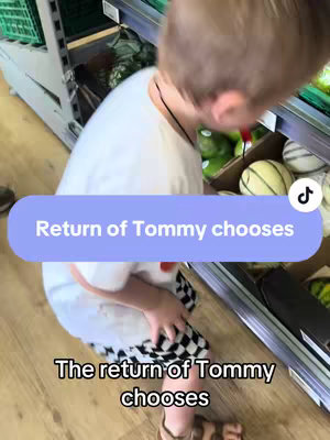 A person, likely a child, is bent over, looking at some produce in a store. The person is wearing a white t-shirt and plaid shorts. Some text is overlaid on the picture indicating the returning of a "Tommy Chooses" segment, with the TikTok logo in the corner.