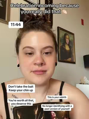 A woman with dark hair and multiple piercings is centered in a selfie-style shot. She is looking towards the camera with a neutral expression, and text boxes are overlaid with messages. The background shows a room with a framed artwork.