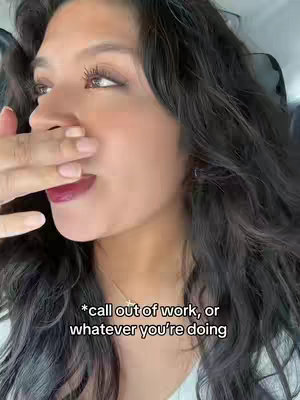 A woman is shown in a selfie, covering her mouth with her hand with dark lipstick. The background is slightly blurred. White text overlay at the bottom states, "*call out of work, or whatever you're doing".