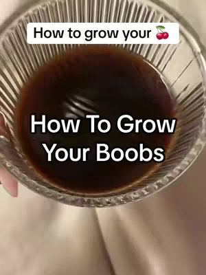 The cover image presents a close-up shot of a clear glass filled with a dark liquid, likely a drink or infusion. Overlayed at the top is a white rectangular box with the text "How to grow your" followed by a cherry emoji. Below this, large white text spells out "How To Grow Your Boobs". The overall composition creates an impression of warmth and intrigue, enhanced by the slightly blurred background.