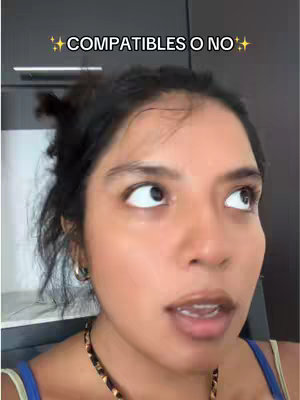 A woman with dark hair and a blue top is looking up and slightly to the right with an open mouth, as if talking. Overlayed text reads “COMPATIBLES O NO” with star emojis on either side. The background is indistinct.
