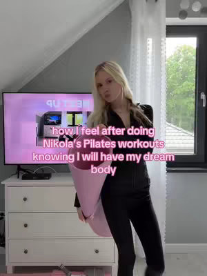 A woman stands in front of a TV and a white dresser holding a bouquet of pink flowers. Text overlays that wraps around the woman