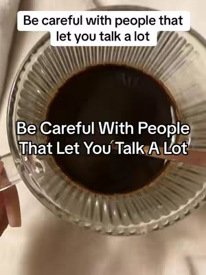 An overhead shot of a clear glass cup filled with dark brown liquid, likely coffee. The image is well-lit, and the focus is sharp on the liquid. In the upper portion of the image, text is overlaid. The photo has a clean, simple aesthetic.