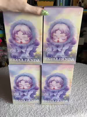 The image showcases four boxes of the Skullpanda L’impressionnisme blind box series, arranged in a two-by-two grid. Each box features the same artwork: a character with closed eyes, wearing a purple hooded outfit adorned with a floral, layered design, creating a distinct visual style.