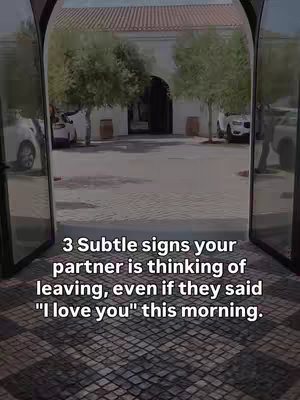 The cover image presents a wide shot looking through two open glass doors. The doors offer a view of a paved courtyard framed by a building with a red tile roof. Trees flank the courtyard, with parked cars visible. The text overlayed is white sans-serif font with black outlines.