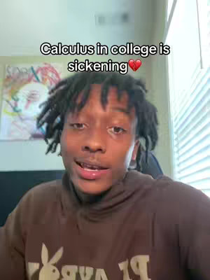 A young Black man is centered in a selfie-style shot. He wears a brown hoodie, with a white logo prominently displayed on the chest. The background is a blurred mix of colors, with a partial view of a painting and window blinds. Text overlayed on the image reads, "Calculus in college is sickening ❤️."