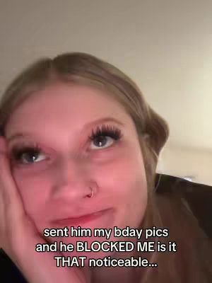 A close-up shot of a young woman's face. She has long lashes, a nose ring, and blonde hair. Text overlays towards the bottom of the image.