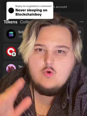 A medium shot of a young man with fair skin, light-blonde hair with dark roots, and a short beard, who is speaking and gesturing towards the camera. Behind him is a screen showing a mobile app interface with crypto currency information.