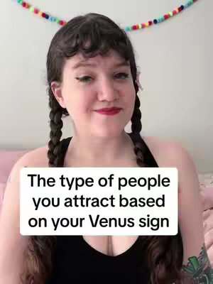 A selfie of a woman with fair skin and dark hair styled in two braids, smiling and posing. She is wearing makeup, including eyeliner and lipstick. The background features a multi-colored string of balls, and a white rectangle with a black caption that reads 'The type of people you attract based on your Venus sign'.