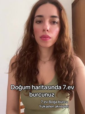 A woman with long, wavy brown hair is centered in a vertical video frame. She has fair skin and a neutral expression. In the lower part of the frame, text overlays read "Doğum haritasında 7.ev burcunuz" and "7.ev Boğa burcu Yükselen akrepler". The background is a neutral, possibly indoor setting.