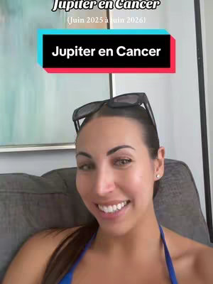 A woman with dark hair and sunglasses on top of her head smiles at the camera. Text overlays at the top state "Jupiter en Cancer" and "(Juin 2025 à juin 2026)" in a colorful rectangle. The background is a blurred interior.