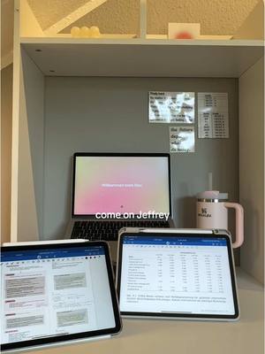 The image shows a desk neatly organized with a laptop and two tablets. A pink Stanley mug sits nearby. At the top of the image, there is a white cabinet, and on its gray background, some sticky notes are placed. The text 'come on Jeffrey' is overlaid on the image.