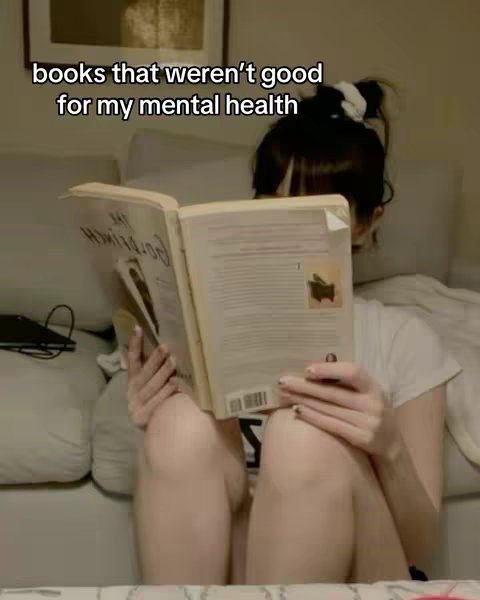 A woman is seated, holding an open book in front of them. The text overlay at the top reads, 'books that weren't good for my mental health.'